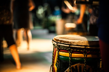 A close up selective focus view of a colorful Arfican doun doun drum, aka dun dun, doundoun, dunun. Seen in music bar with blurry people in background. © Valmedia