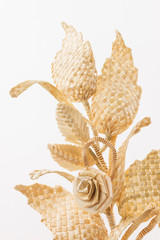 Obraz premium Decoration of straw on a white background. Branch with leaves and flowers is made of straw. Decor. Fragment closeup. Copy space 