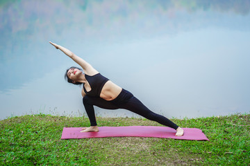 Young woman practicing yoga at lake in outdoor. Beautiful girl practice yoga in nature..