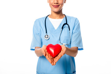 Cropped view of african american nurse with stethoscope showing decorative heart and smiling isolated on white