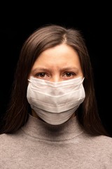 a woman in a mask , a tense, restless look at the camera. concern about a coronavirus infection , an attempt at protection. Studio portrait close -up. vertical photo