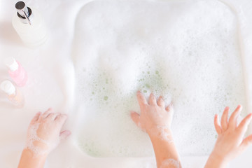 Little girls wash their hands in the sink with soap in the foam. Protection against coronovirus...