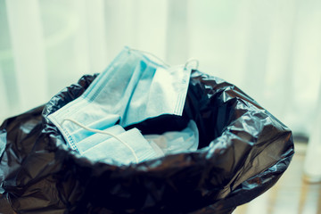 The used mask is cut to prevent reuse in the bucket. Close up of used face masks, medical face masks. Useless coronavirus face mask.