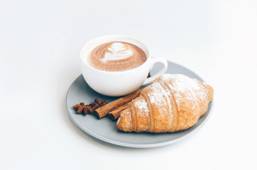 Fresh baked croissant with coffee cup and latte art, cinnamon