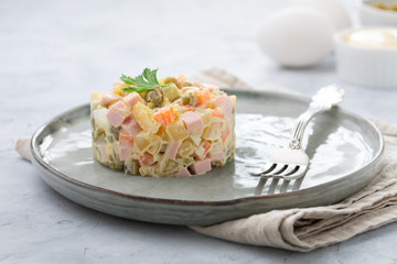 Russian salad Olivier with mayonnaise served in culinary ring on plate. Light background.