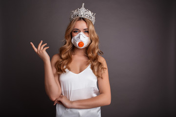 Coronavirus concept. Woman is wearing mask and crown on a gray background. Outbreak of the corona virus in China, illness. Epidemic.
