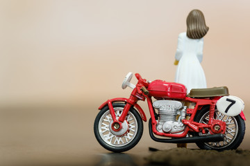 vintage style red color motorbike and girl figure toy closeup view