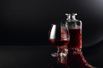 Glass of brandy and a carafe on a dark background.