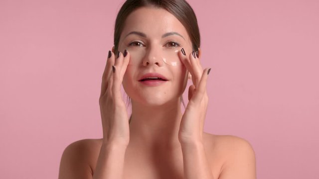 30s brunette woman makes an under eye massage with gel eye patches on. Self-care concept