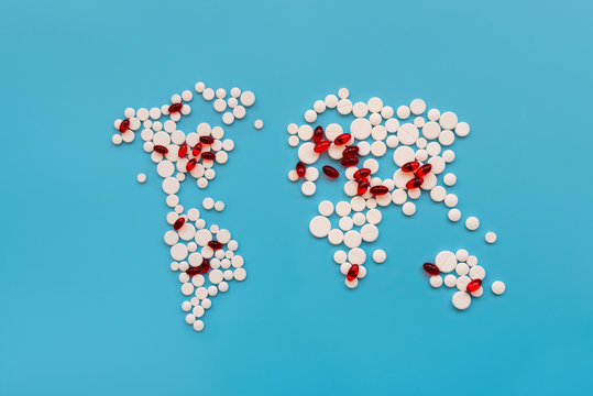 Covid-19. World map shape make from white pills with red pills as areas infected by virus on blue background. Flu, illness concept