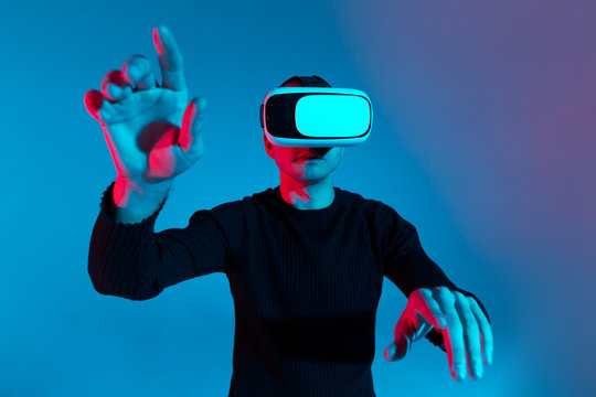 VR, AR, MR, XR- Future technology. Neon. European man's in VR-glasses in neon on gradient background. Male portrait. Concept of human emotions, facial expression, modern gadgets and technologies