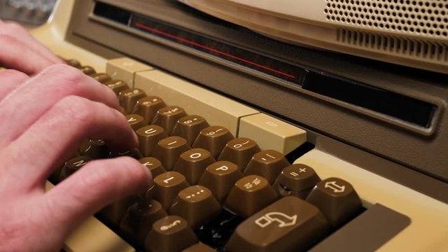 Close up of hands typing on a retro keyboard  from 70s 80s computer. Old technology concept.