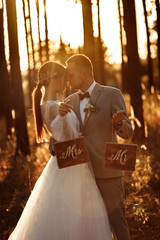 Wonderful wedding couple in the forest at sunset. Mister and Missis.