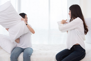 Two Asian girls doing pillow fight in bedroom as childhood. Lifestyles and People concept. Relation and friendship theme. Couple and friends concept. LGBT and people lifestyle