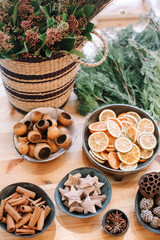 Base for Christmas wreath. Christmas decorations. Florist making Christmas wreath. View of female hands make a wreath. Decorations for wreath. Oranges, flowers red berries, wooden stars.