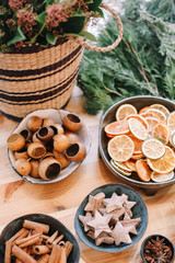 Base for Christmas wreath. Christmas decorations. Florist making Christmas wreath. View of female hands make a wreath. Decorations for wreath. Oranges, flowers red berries, wooden stars.