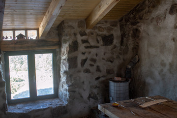 interior del refujio de montañeros chozo aranguez donde las paredes son de piedra natural y hay una pequeña y antigua estufa de leña