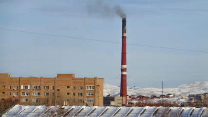 Apartment building  and factory chimnet. Winter snow. Blue sky. Ust-Kamenogorsk (Kazakhstan)