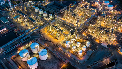 Aerial top view oil and gas tank with oil refinery background at night, Business petrochemical industrial, Refinery factory oil storage tank and pipeline,  Ecosystem and healthy environment concepts.