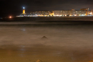 panoramica de la ciudad de la coruña con el faro de  la toore de hercules la fondo y un mar revuelto visto desde la playa de riazon
