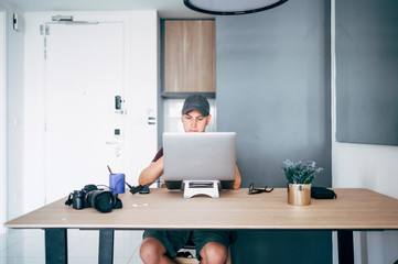 Man working from home on a laptop computer sitting at a desk surfing the internet