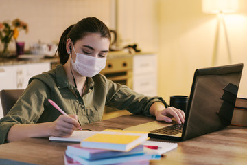 woman working at home with medical mask on face. coronavirus quarantine remote home working concept.