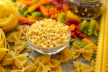 Italian raw pasta, types of pasta. Light background, top view, close-up. Farfalle, fettuccine, fusilli, colored pasta, tagliatelle.