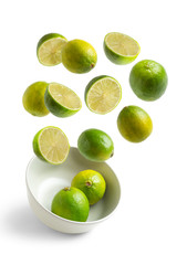 limes flying in white bowl on white isolated background