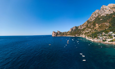 Fototapeta na wymiar Aerial view of coastline of the village of Nerano. Private and wild beaches of Italy. Turquoise, blue surface of the water. Vacation and travel concept. Boats on raid in bay. Copy space. Summer day
