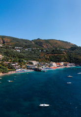 Aerial view of coastline of the village of Nerano. Private and wild beaches of Italy. Turquoise, blue surface of the water. Vacation and travel concept. Boats in bay. Copy space. Vertical photo