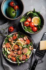 Salad with fried shrimp, tomatoes, avocado and arugula