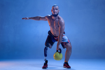 Athlete with disabilities or amputee isolated on blue studio background. Professional male...