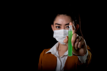 Fototapeta na wymiar Businesswoman of young Asia woman putting on a respirator N95 mask with the hand that applying alcohol spray from the plastic bottle or anti bacteria to prevent the spread of germs at black background