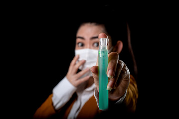 Businesswoman of young Asia woman putting on a respirator N95 mask with the hand that applying alcohol spray from the plastic bottle or anti bacteria to prevent the spread of germs at black background