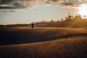 Fototapeta na wymiar Maspalomas, Canary Islands. Man stands in desert dunes at sunset with very orange tones