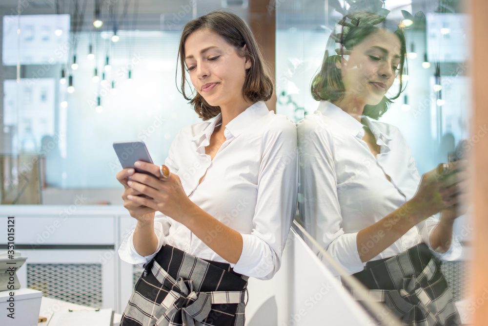 Wall mural Portrait of beautiful business woman using mobile phone in office