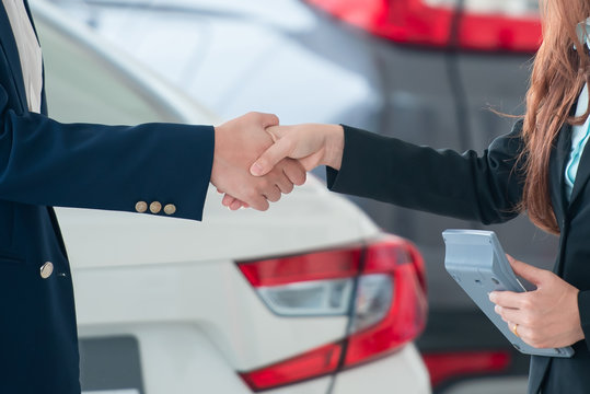 Pictures of Asian customers and salespeople hand in hand happy to buy new cars that make sales agreements with car dealers at car dealers.