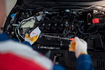 Asian car mechanic in an auto repair shop is checking the engine. For customers who use cars for...