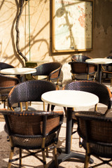 Vertical picture of tables and chairs on street in restaurant in lourmarin, one of the most beautiful villages of France, Provence in sunny day with map of Lourmarin on stone wall on background.