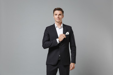 Obraz na płótnie Canvas Handsome confident young business man in classic black suit shirt posing isolated on grey background studio portrait. Achievement career wealth business concept. Mock up copy space. Looking camera.