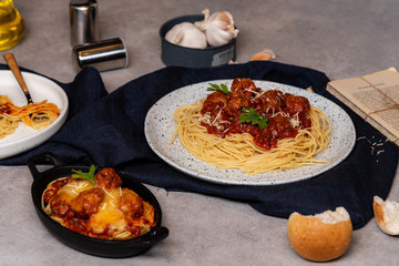 Homemade spaghetti or pasta with meatball and cheese in tomato sauce  placed in a white dish. On dark blue tablecloth on the table with Bread Pie.