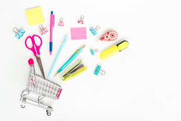 Bright stationery objects in mini supermarket cart on white background