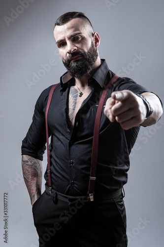 Ragazzo Barbuto Con Tatuaggi In Tutto Il Corpo, Vestito Con Camicia Nera E  Bretelle Rosse, Indica Con Atteggiamento D'accusa, Isolato Su Sfondo Grigio  1 Wall Mural |-alex.pin