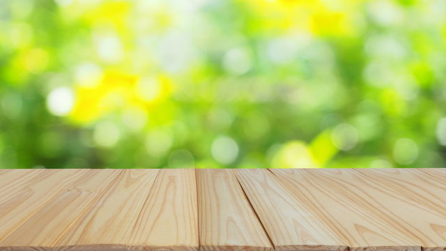 wood table top on blur and bokeh abstract green tree in the garden for banner design or natural montage display product background with copy space.