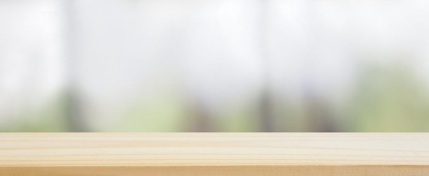 wood plank table top on blur abstract green tree , leaves and kitchen window and see view the garden behind using for banner design and natural background or montage display product layout