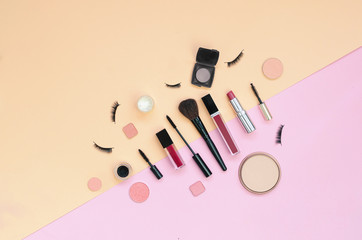 Colorful cosmetics lying on pink and yellow background. Flatlay