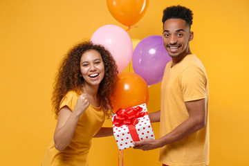 Joyful friends couple african american guy girl isolated on yellow background. Birthday holiday...