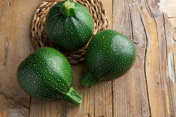 Aerial view of three round zucchini on rustic wooden board with copy space horizontal