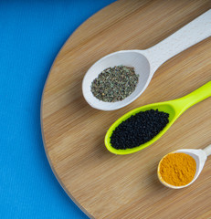 spice- turmeric basil and black cumin in spoons on the kitchen wooden board