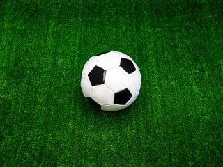 Classic black and white soccer ball on green artificial grass, alone